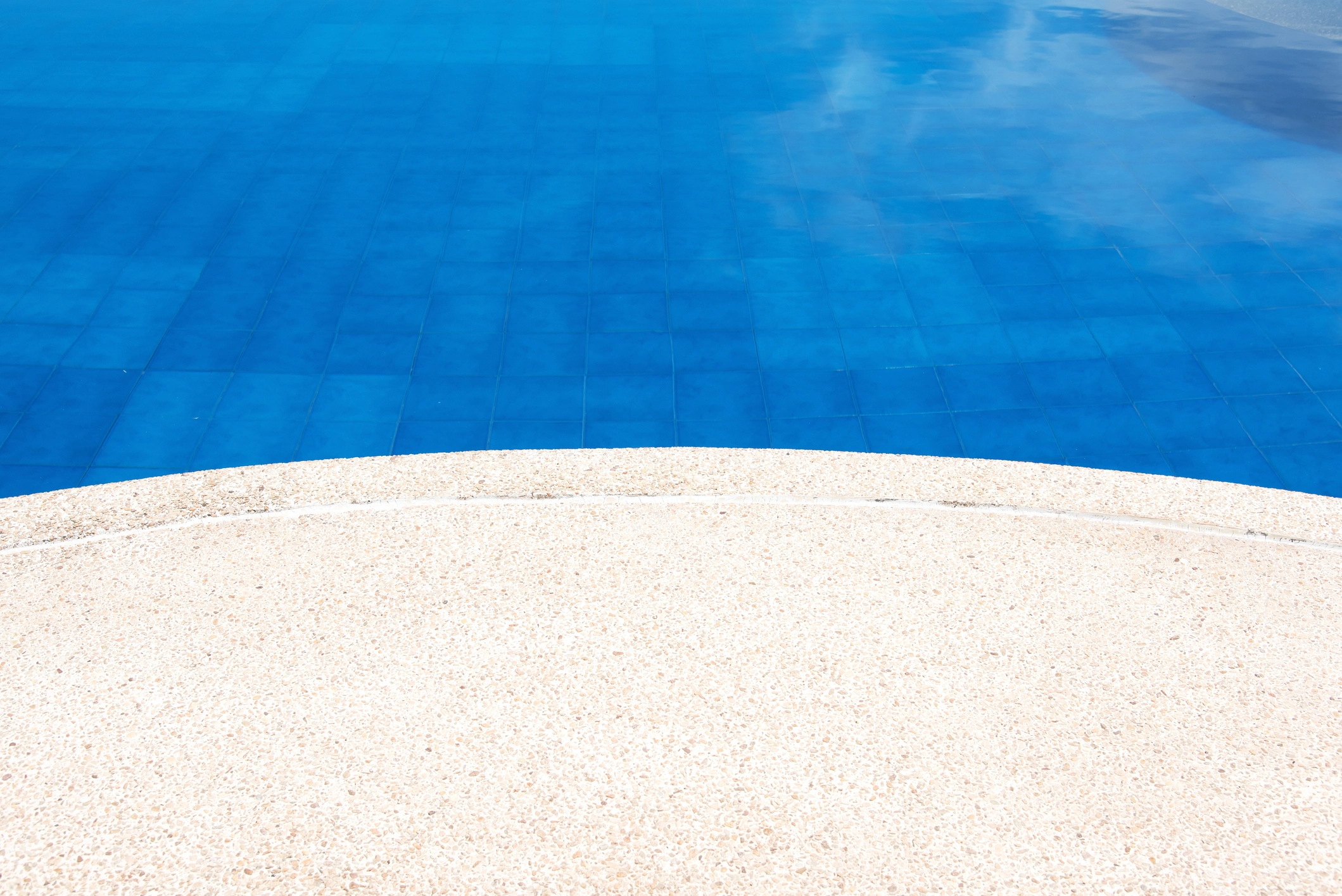 Abords d'une piscine sublimés par une moquette de pierre, alliant élégance et sécurité antidérapante.
