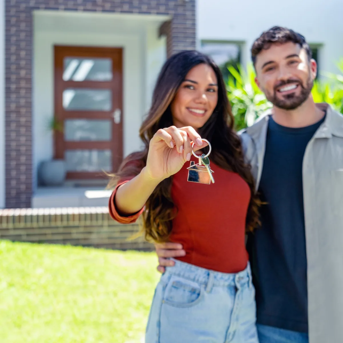 Un couple heureux de devenir propriétaire, tenant les clés devant leur nouvelle maison
