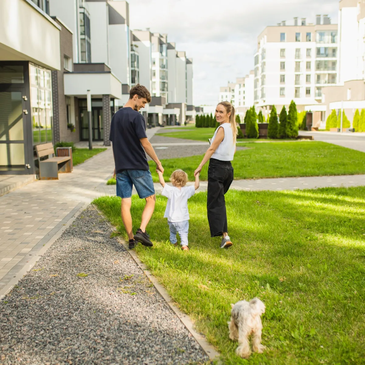 un couple promène son enfant au rez de chaussée d'un immeuble