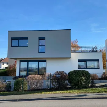 Maison contemporaine à l’architecture cubique et épurée, située dans un quartier résidentiel calme et verdoyant
